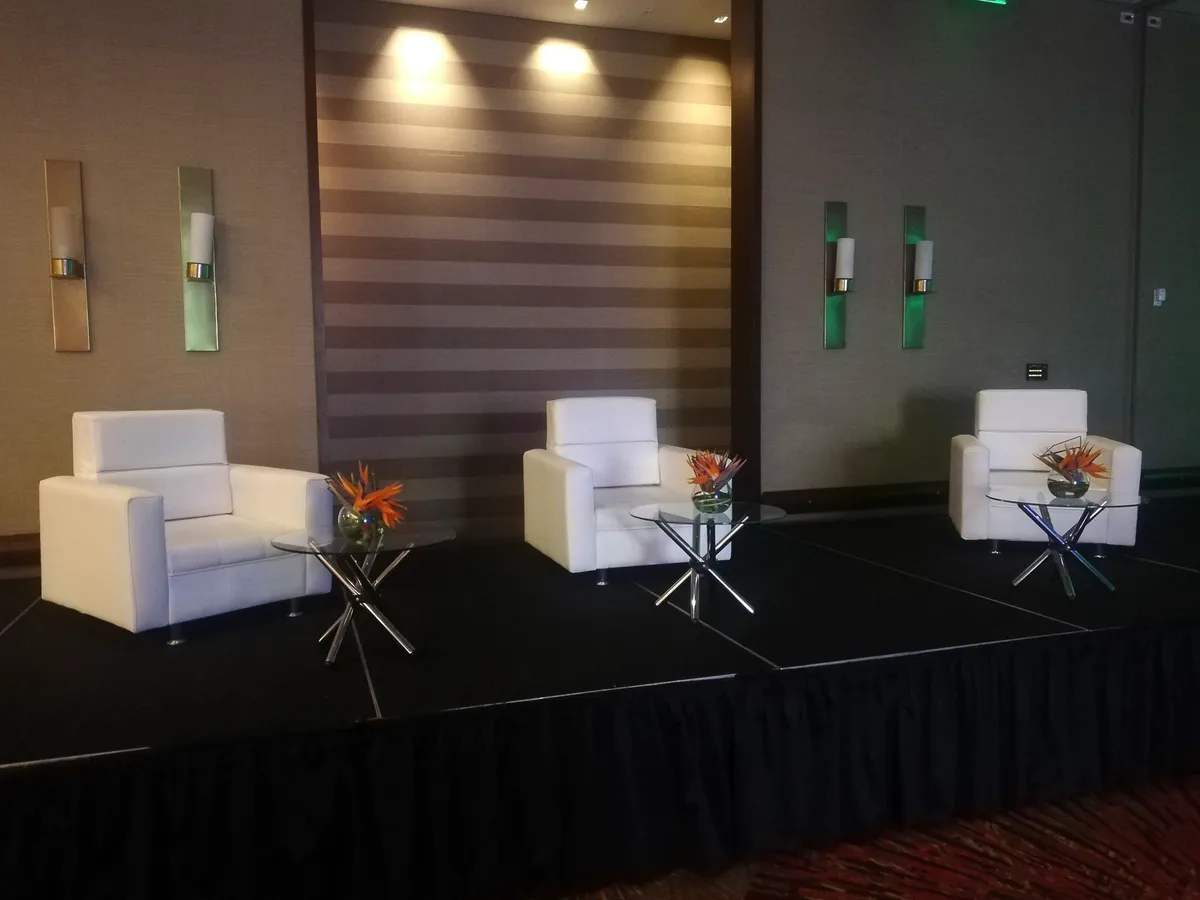 Sala lounge blanca con mesas auxiliares y arreglos florales para evento